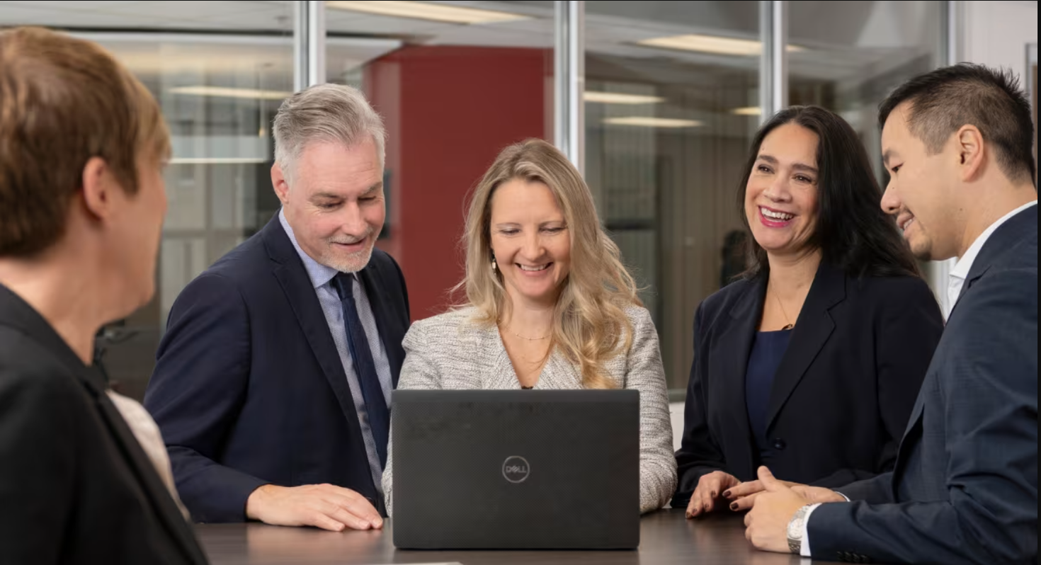 Professionals gathering around a laptop