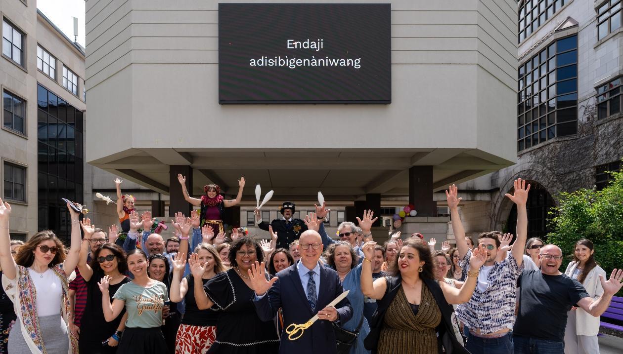 Inauguration of the Arts District at the University of Ottawa with outgoing dean Kevin Kee, joined by dignitaries, Faculty of Arts staff, and local artists, in front of the sign “Endaji adisibigenàniwang”.