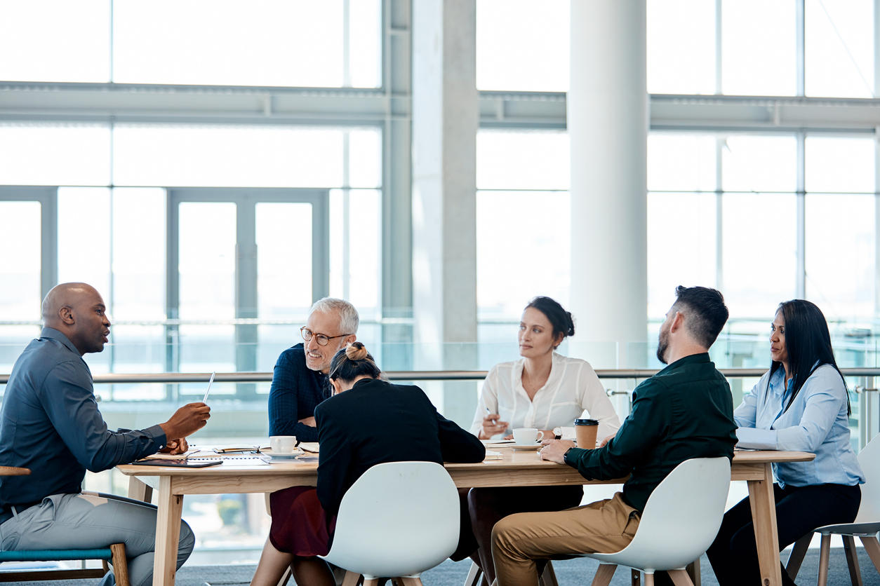 A professor leads a conversation with other professors around a table.