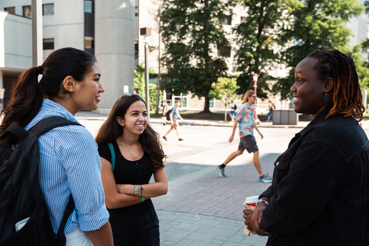 3 students talking to each other on campus.