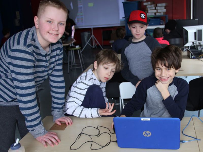 Un groupe d'étudiants autour d'un ordinateur portable bleu.