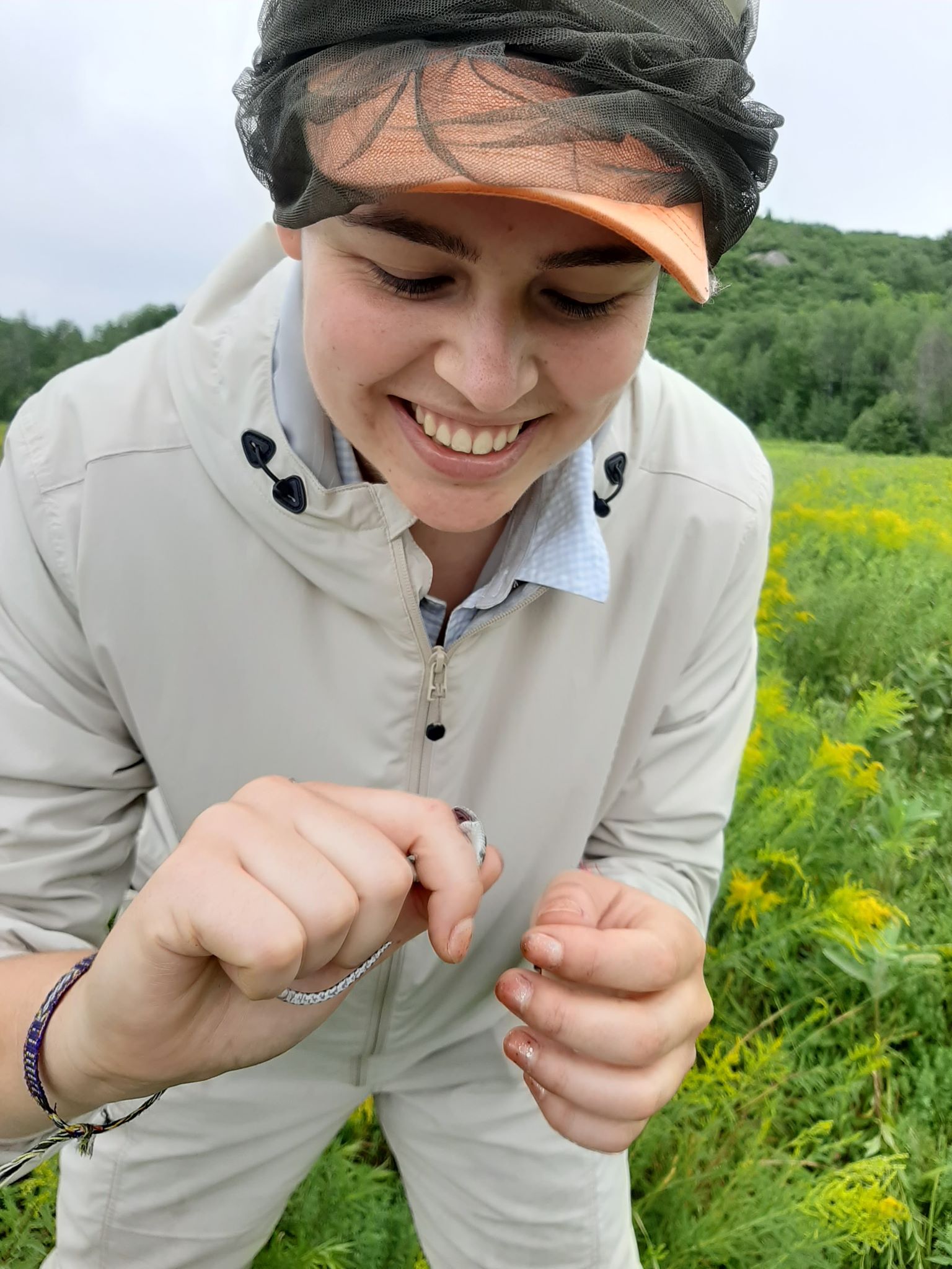 Student Lorena Fernandez holding a small snake in a field