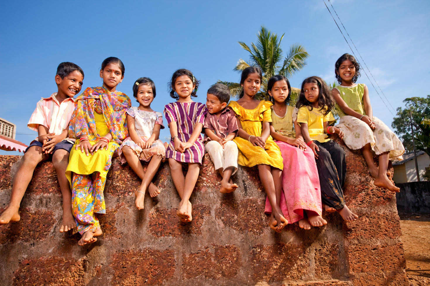Indian children sitting on rock smiling.