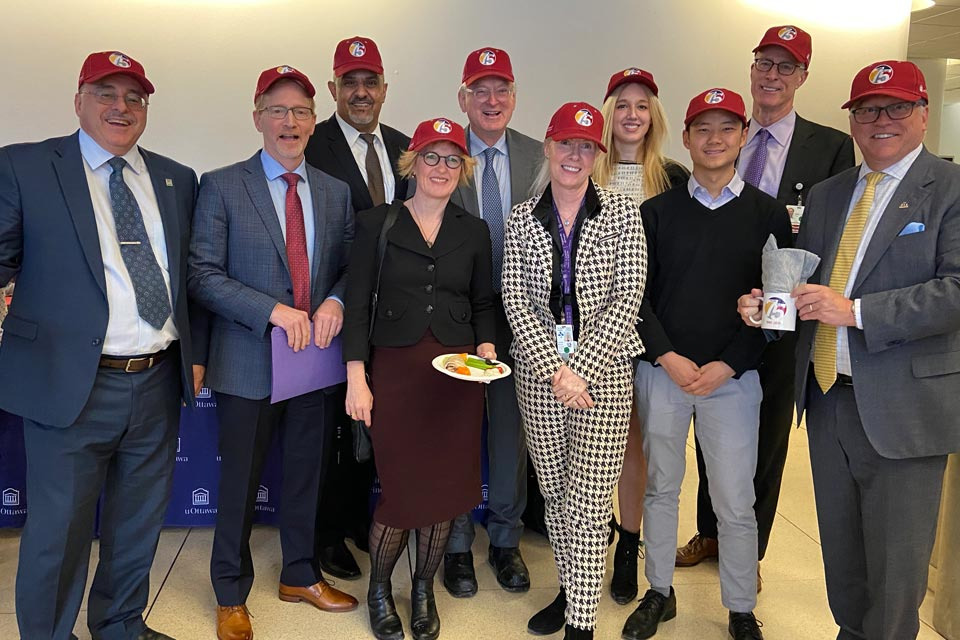 A group of leaders, faculty members and students pose with hats