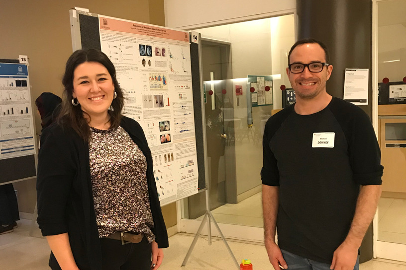 Two people standing in front of a research poster