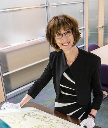 France Martineau stands in a map library reviewing a centuries-old map.