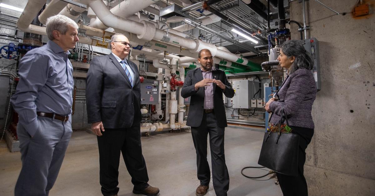 University of Ottawa Energy and Environment Manager Faizal Sudoollah talks to three Enbridge Gas executives in a mechanical room